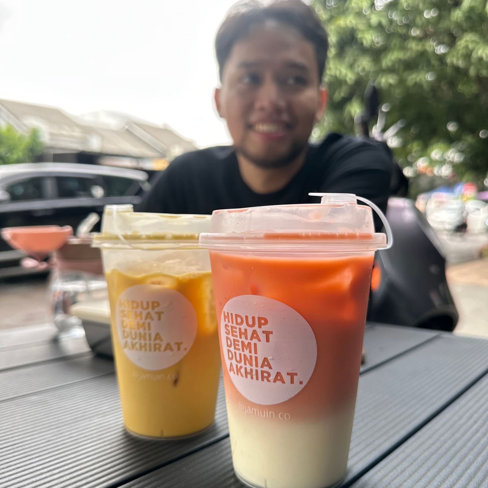 Pelanggan memegang dua gelas minuman Jamuin di depan gerai