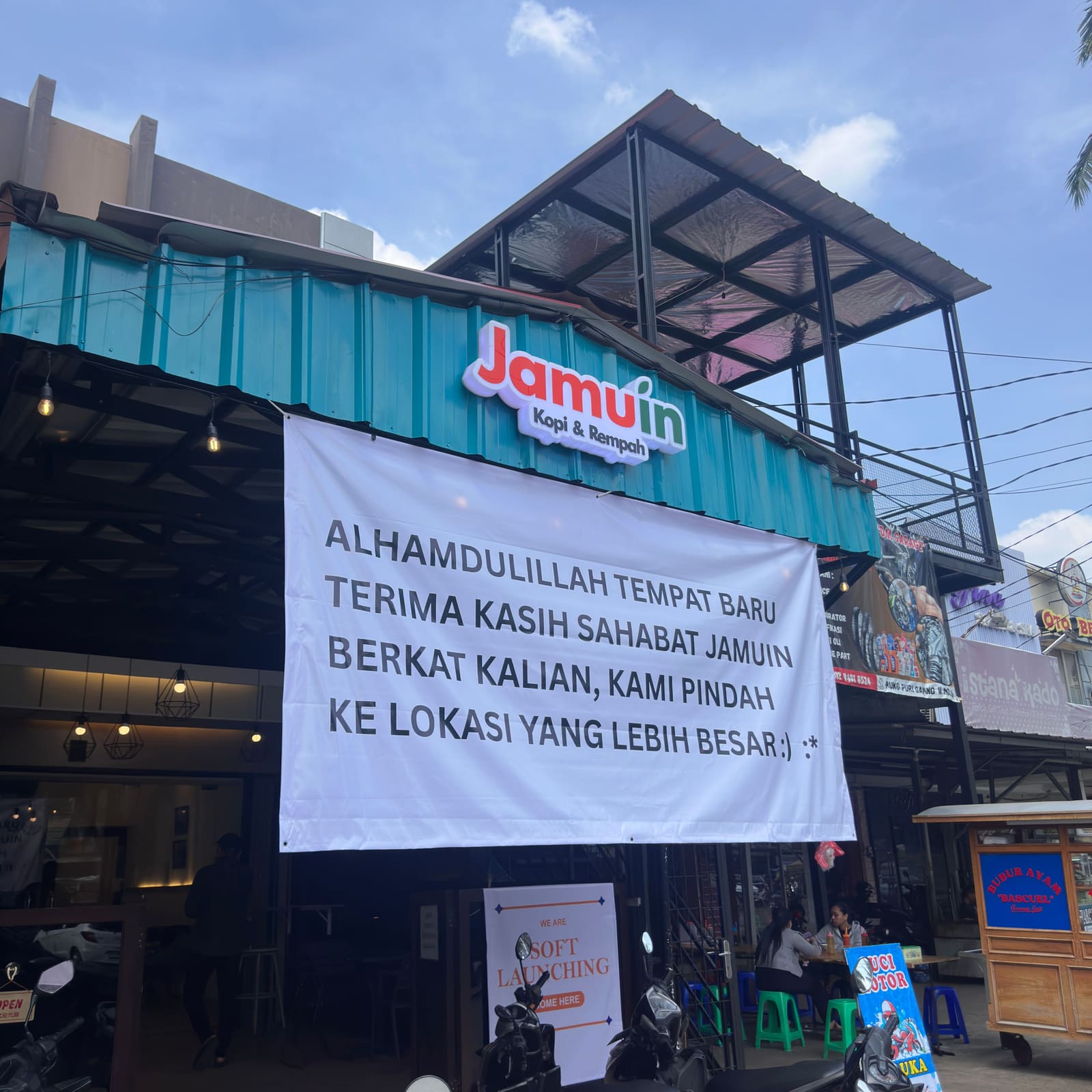Papan nama gerai Jamuin Kopi & Rempah dengan spanduk ucapan terima kasih di lokasi baru