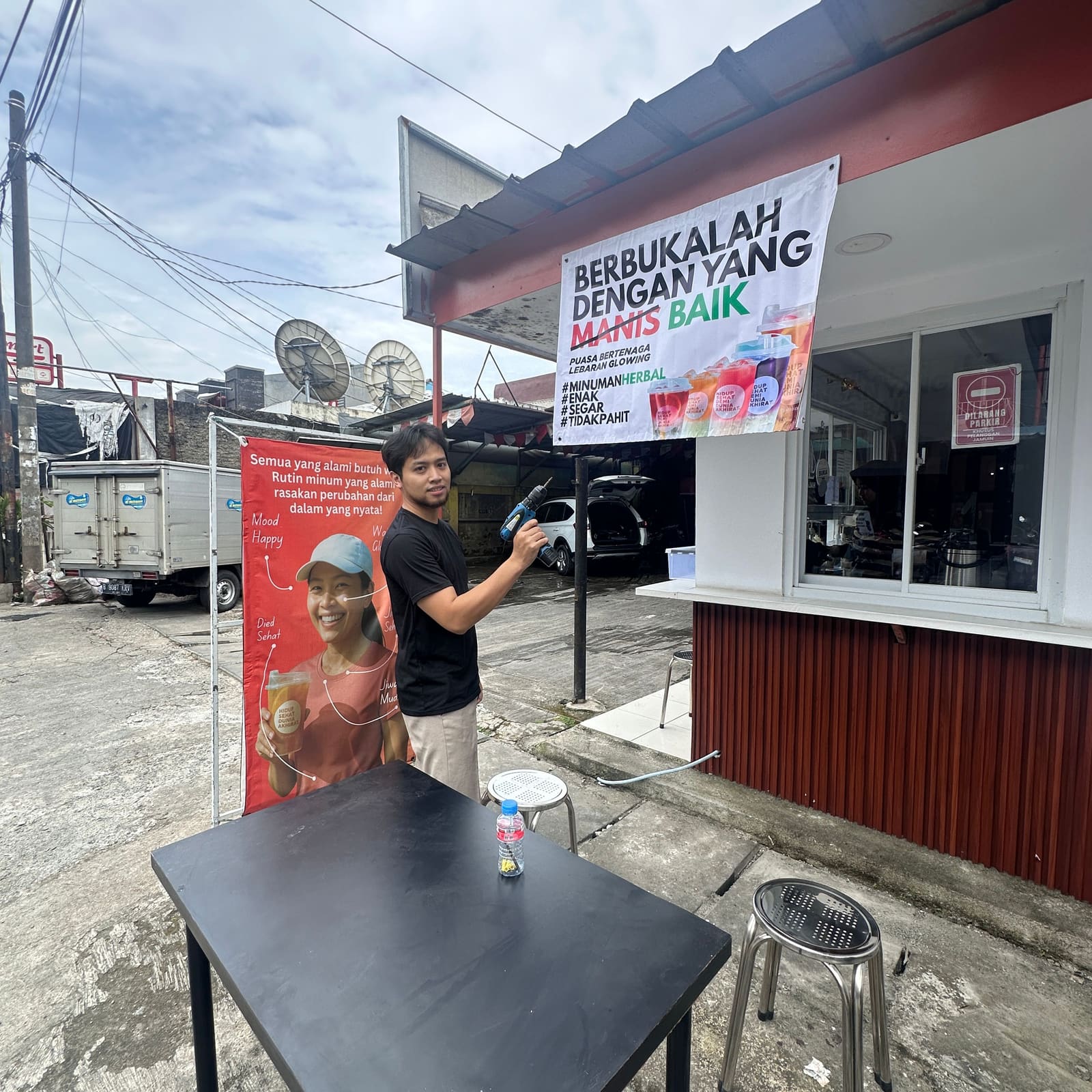 Anggota tim Jamuin memasang spanduk promo di depan gerai