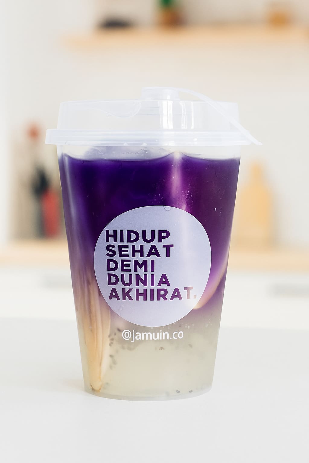 Segelas Teh Bunga Telang Jamuin dengan gradasi ungu dan lapisan bening di bawahnya